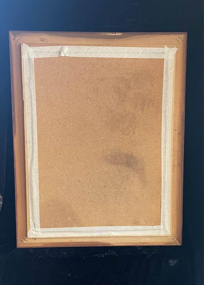 May include: A wooden picture frame with a brown cardboard backing. The frame has a white tape border around the edge.