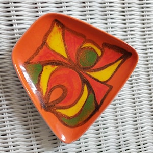 May include: Orange ceramic dish with a diamond shape and a colourful floral design. The design features yellow, red, and green elements with brown outlines. The dish has a glossy finish and is likely vintage.