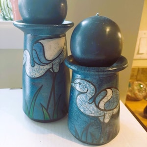 Könnte beinhalten: Zwei blaue Kerzenhalter aus Keramik mit weißen und blauen Vogelmotiven. Jeder Halter hat oben eine runde, dunkelblaue Kerze.