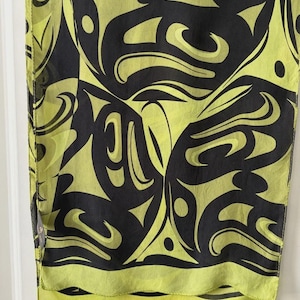 May include: A rectangular scarf featuring a bold, repeating graphic pattern in black and lime green. The design consists of fluid, interconnected shapes and curved lines that create a continuous, abstract motif across the entire fabric surface.