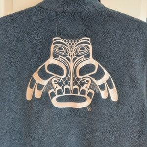 May include: A dark blue fleece jacket with a white embroidered owl design on the back. The owl is in a traditional Native American style.