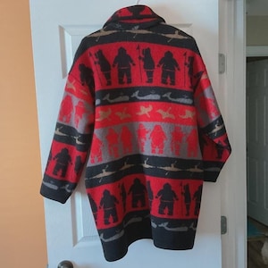 Peut inclure: Un cardigan à manches longues et ouverture frontale, orné d'un motif répétitif de silhouettes noires de personnes tenant des lances, de baleines grises et d'oiseaux fauves sur un fond rouge et noir vif. Il possède un col châle et un ourlet droit.