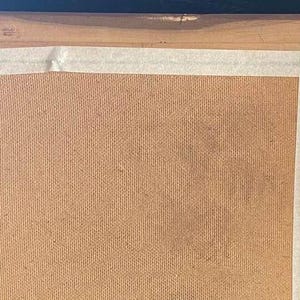 May include: A wooden picture frame with a brown cardboard backing. The frame has a light brown finish and is covered with white tape.