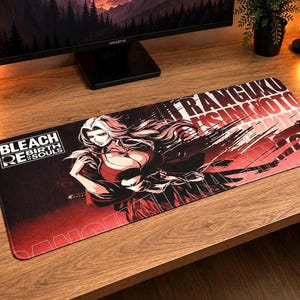 May include: A rectangular desk mat featuring a graphic illustration of the character Rangiku Matsumoto from Bleach Rebirth of Souls. The design includes the text Bleach Rebirth of Souls, a red and black color scheme, and stylized Japanese lettering.