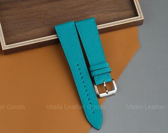 May include: Turquoise leather watch straps with a silver buckle. The straps are displayed on a brown and orange surface. The text "Vitalis Leather Goods" is visible in the image.