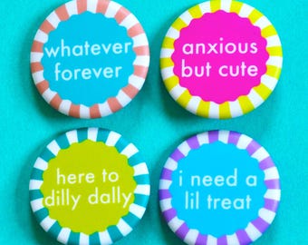 Könnte beinhalten: Vier bunte runde Knöpfe mit weißem Text. Die Knöpfe sagen "whatever forever", "anxious but cute", "here to dilly dally" und "i need a lil treat".