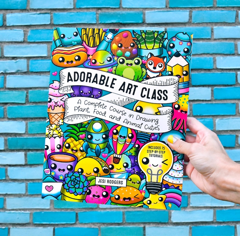 Pode incluir: Uma capa de livro colorida intitulada "Adorable Art Class" com desenhos de desenhos animados de comida, plantas e animais. A capa inclui o texto "Um Curso Completo de Desenho de Plantas, Alimentos e Animais Fofos" e "Inclui 75 Tutoriais Passo a Passo".
