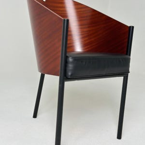 Puede incluir: Una silla de madera con respaldo curvo y patas de metal negro. La silla tiene un asiento de cuero negro.