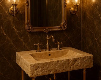 May include: A gold-toned bathroom vanity with a stone countertop and a single sink. The vanity has a decorative, ornate mirror above it with two wall sconces on either side.