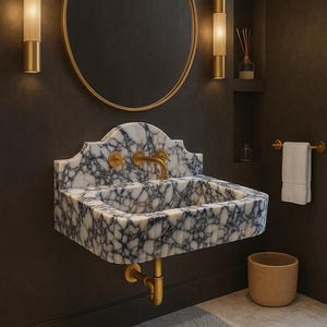 May include: A marble sink with a white and gray pattern, gold fixtures, and a matching round mirror. The bathroom features gold sconces, a towel rack, and a woven basket. The overall design is luxurious and modern.