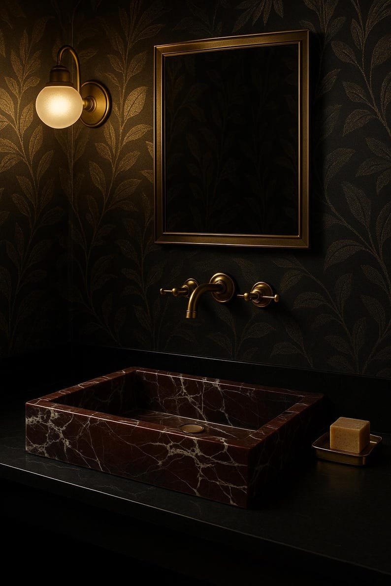 Op de afbeelding: Een donkerbruine marmeren badkamer wastafel met een gouden kraan en een zeepbakje. De wastafel is geplaatst tegen een donkere achtergrond met goudkleurig behang.