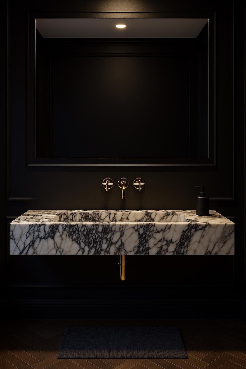 May include: A modern bathroom sink with a marble countertop featuring black veining. The sink has gold fixtures and a black soap dispenser. The dark walls and large mirror create a luxurious, minimalist aesthetic.