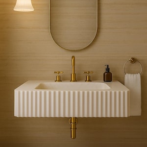 May include: A modern bathroom sink with a fluted design, gold fixtures, and a matching oval mirror. The sink has a built-in soap dispenser and a towel ring. A cream-colored rug sits on the floor, and a pendant light hangs above.