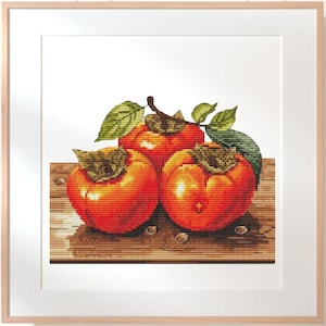 May include: Three ripe orange persimmons on a wooden surface. The persimmons are arranged in a cluster, with one on top of the other two.