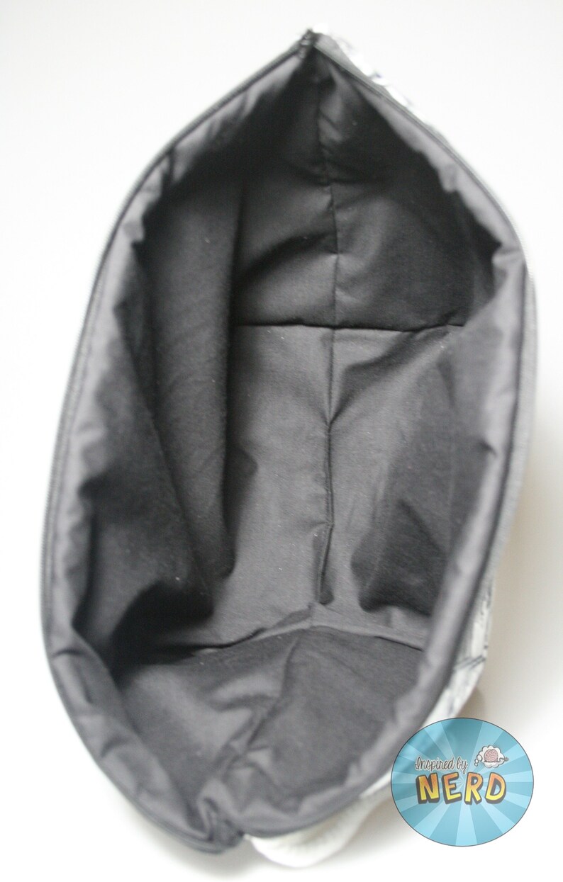 May include: Black fabric tote bag with a white lining and a black and white graphic print of a robot with the text "Inspired by Nerd" on the bottom right corner.