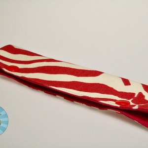 May include: A red and white striped fabric pencil case with two pink buttons.