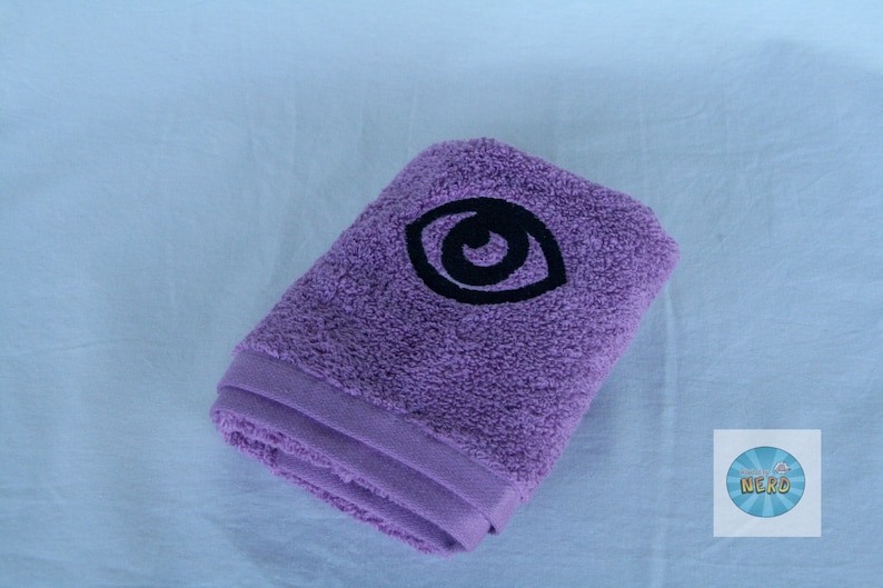 May include: A purple towel with a black embroidered eye design.