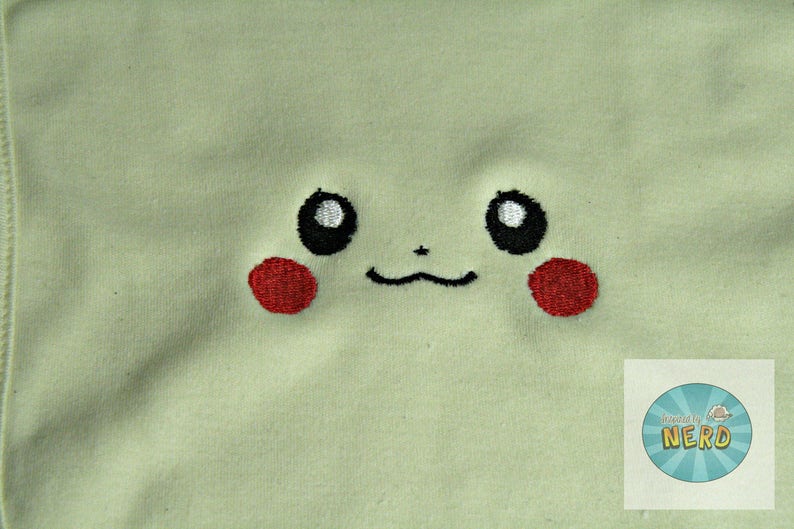 K&ouml;nnte beinhalten: Ein hellgr&uuml;ner Stoff mit einem gestickten Pikachu-Gesicht. Das Gesicht hat schwarze Augen mit wei&szlig;en Highlights, eine schwarze Nase und einen schwarzen l&auml;chelnden Mund. Die Wangen sind rot.