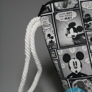 May include: Black and white zippered pouch with a white rope handle. The pouch features a comic book design with Mickey Mouse and the text "You're not the boss of me!"