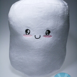 May include: White plush toy shaped like a marshmallow with a smiling face and pink cheeks. The toy has black eyes and a black stitched smile. The toy is labelled "Inspired by NERD".
