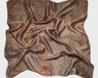 May include: A square silk scarf with a brown and tan color palette. The scarf has a wrinkled texture and features a pattern of leaf-like shapes in shades of orange and brown. The scarf is likely made of a soft, flowing material.