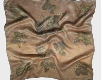 May include: A square, silk scarf in shades of tan and brown, with a leaf pattern. The scarf has a slightly wrinkled texture, and the leaf imprints are in varying shades of green and brown. The overall effect is a natural, organic design.