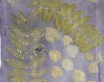 May include: A square, lavender-colored textile with a botanical print. The design features imprints of various leaves in shades of yellow and cream, creating a natural, artistic pattern. The textile's edges are slightly darker, adding depth to the design.