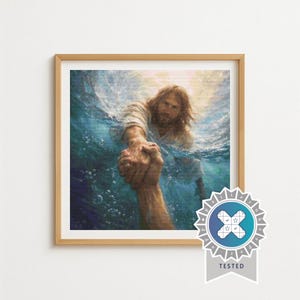 Op de afbeelding: Een ingelijste prent toont een persoon die een hand uitreikt naar een ander in het water. Het kunstwerk gebruikt warme kleuren en benadrukt de handen en gezichten. De afbeelding is geplaatst in een lichtbruine houten lijst.