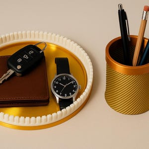 May include: A gold-colored tray with a white rim holds a brown wallet, a black car key, and a wristwatch with a black leather band. A gold and yellow pen holder contains pens and a pencil.