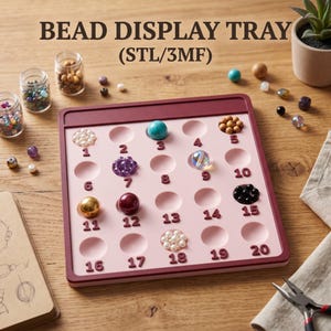 Peut inclure: Un plateau de présentation de perles rose clair carré avec une bordure marron foncé, comportant vingt encoches circulaires numérotées de 1 à 20. Le plateau est marqué BEAD DISPLAY TRAY (STL/3MF) et contient diverses perles colorées.