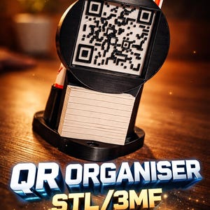 Peut inclure: Organisateur de code QR noir avec une pile de cartes, deux stylos et le texte "QR ORGANISER STL/3MF". L'organisateur est sur une surface en bois. Les stylos sont blancs avec des accents rouges.