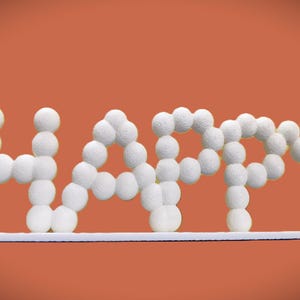 May include: White, textured spheres form the word "HAPPY" against an orange background. The letters are connected and rest on a white, horizontal base. The overall design is simple and cheerful, suitable for home decor.