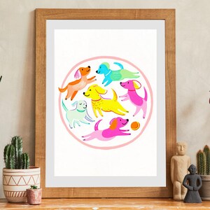 Puede incluir: Una impresión artística enmarcada que presenta un círculo de perros de dibujos animados coloridos. Los perros, en varios colores como naranja, amarillo, rosa y azul, se encuentran sobre un fondo blanco. El marco es de madera clara.