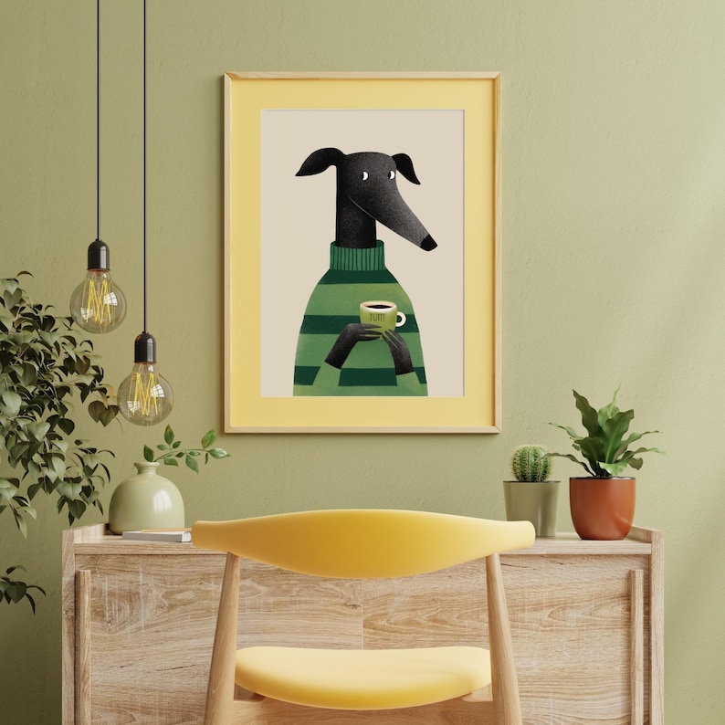 May include: Framed art print featuring a stylized black dog wearing a green and white striped sweater, holding a coffee cup. The artwork has a yellow border and is set against a neutral background. The word "yum" is on the cup.