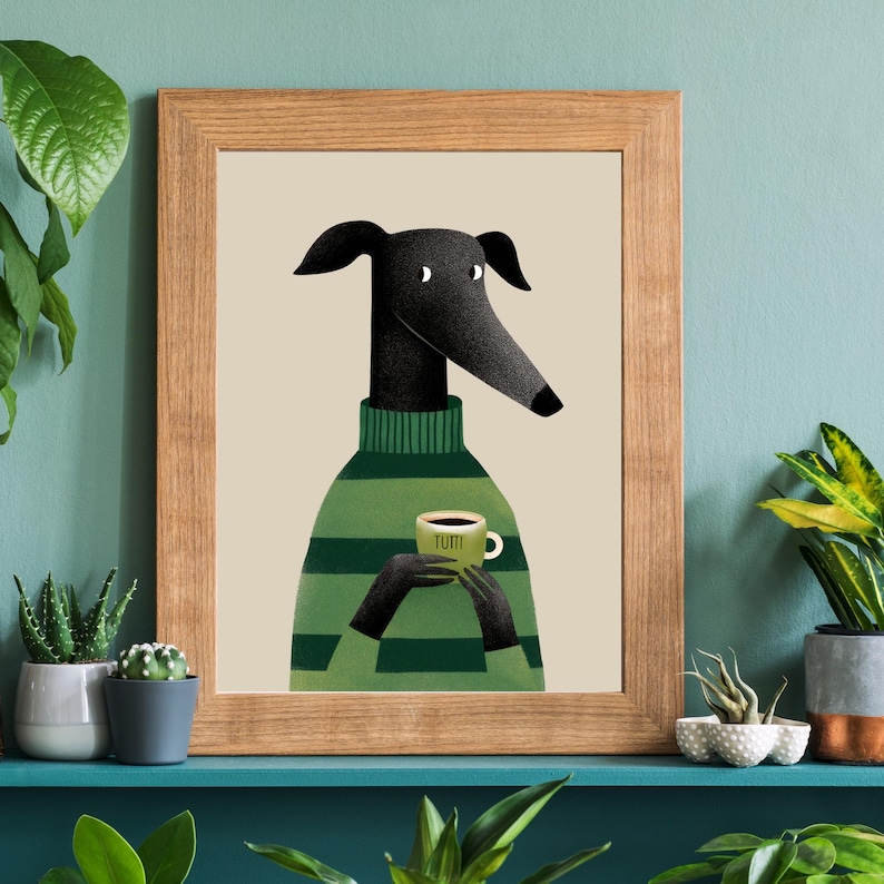 May include: A framed art print featuring a stylized black dog wearing a green and white striped sweater, holding a coffee cup with the word "TUTTI" on it. The artwork has a light beige background and is set in a natural wood frame.