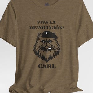 May include: Brown t-shirt with a black illustration of a cat wearing a beret and a microphone. The text "VIVA LA REVOLUCIÓN!" is above the cat, and the name "CARL" is below.