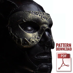 Pode incluir: Uma máscara de couro preta com uma cobertura de olhos e nariz dourada e ornamentada. A máscara tem um design costurado e é embelezada com pequenas pedras escuras. As palavras "PATTERN DOWNLOAD" e um ícone PDF são visíveis.