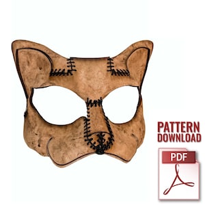May include: A tan leather cat mask with black stitching details. The mask features large eye openings and pointed ears. The text "PATTERN DOWNLOAD" and a PDF icon are visible on the right side.