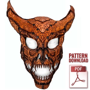 May include: A detailed, orange-brown demon mask with large horns, sharp teeth, and intricate carvings. The mask has white eye openings and is designed with a menacing expression. The image includes the text "PATTERN DOWNLOAD" and a PDF icon.