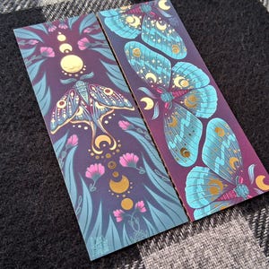 Marcapáginas de lámina dorada con motivos de polillas y plantas con lunas