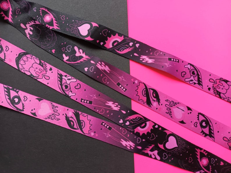 May include: Three pink and black patterned ribbon lanyards with a gradient background and black and white eye and heart designs. The text "Sugar Daddy" is printed on one of the lanyards.