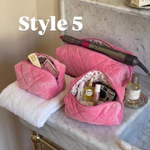 May include: Three quilted hot pink velvet cosmetic bags with floral interior lining. The bags contain various beauty products, a hair styling tool, and a small camera. The text "Style 5" is visible in the upper left corner of the image.