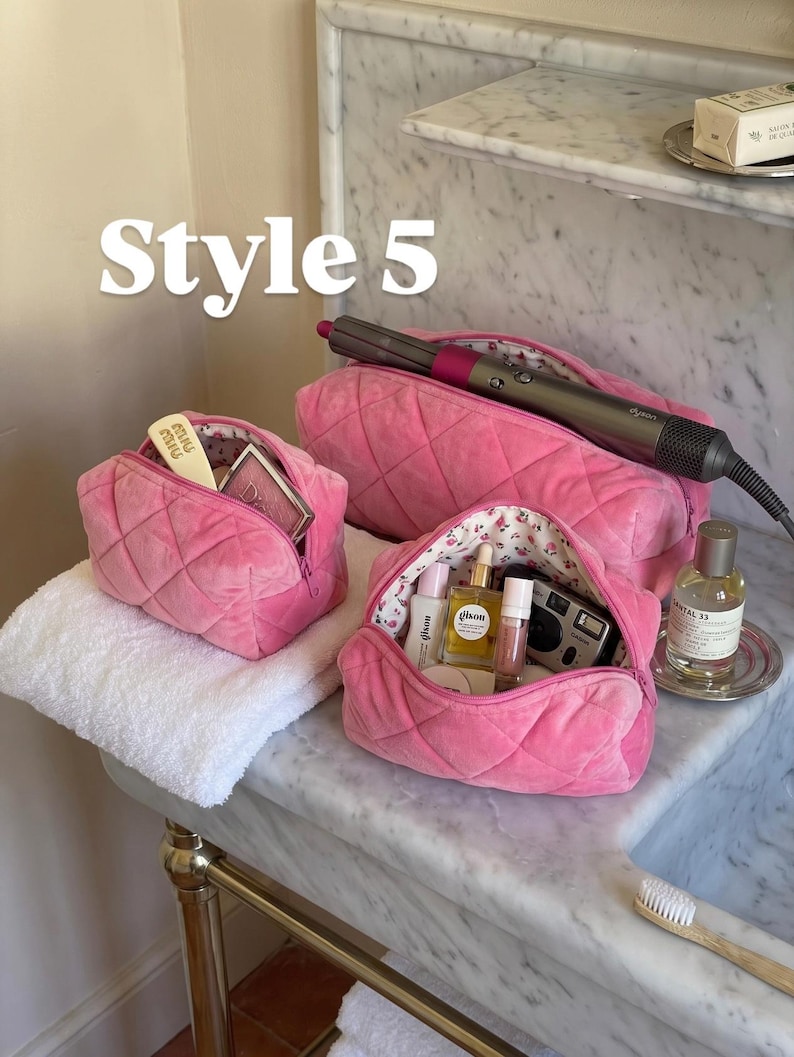 May include: Three quilted hot pink velvet cosmetic bags with floral interior lining. The bags contain various beauty products, a hair styling tool, and a small camera. The text "Style 5" is visible in the upper left corner of the image.