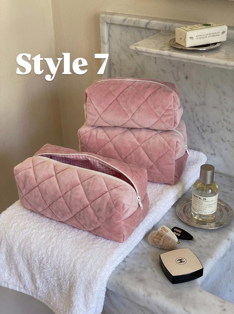 May include: Three dusty pink quilted velvet cosmetic bags with white zippers and a pink and white gingham interior lining. The text "Style 7" is visible in the upper left corner. The bags are rectangular with a soft, plush texture.