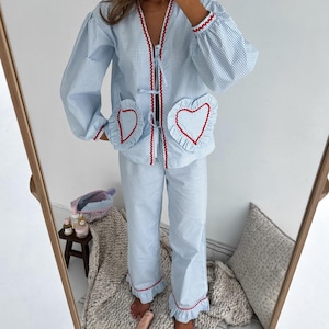 Puede incluir: Conjunto de pijama de cuadros vichy azul claro y blanco con ribete rojo. La parte superior tiene cuello en V, mangas largas y bolsillos en forma de coraz&oacute;n. Los pantalones tienen un dobladillo con volantes. El conjunto est&aacute; hecho de una tela suave y c&oacute;moda.