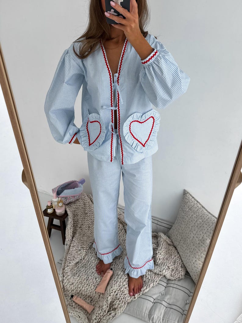 Puede incluir: Conjunto de pijama de cuadros vichy azul claro y blanco con ribete rojo. La parte superior tiene cuello en V, mangas largas y bolsillos en forma de coraz&oacute;n. Los pantalones tienen un dobladillo con volantes. El conjunto est&aacute; hecho de una tela suave y c&oacute;moda.