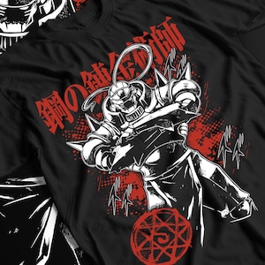 May include: Black t-shirt featuring a detailed illustration of a character in a suit of armor, with red Japanese text and accents. The design includes a red alchemic circle at the bottom. The artwork is in a bold, graphic style.