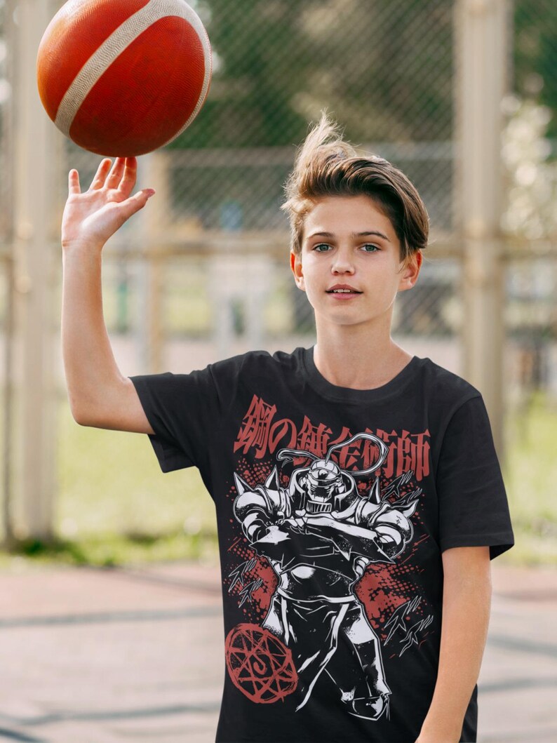 May include: Black t-shirt featuring a graphic of a character from the anime series Fullmetal Alchemist, with Japanese text in red. A red and white basketball is being spun on a finger.