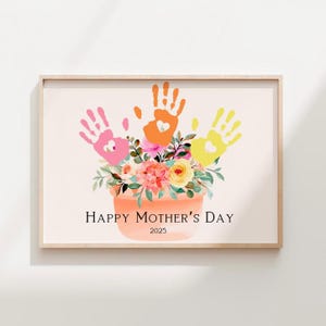 Puede incluir: Una obra de arte de huellas de manos coloridas con tres huellas de manos en rosa, naranja y amarillo, formando un ramo de flores en una maceta de terracota. El texto "Happy Mother's Day 2025" está debajo de la maceta.