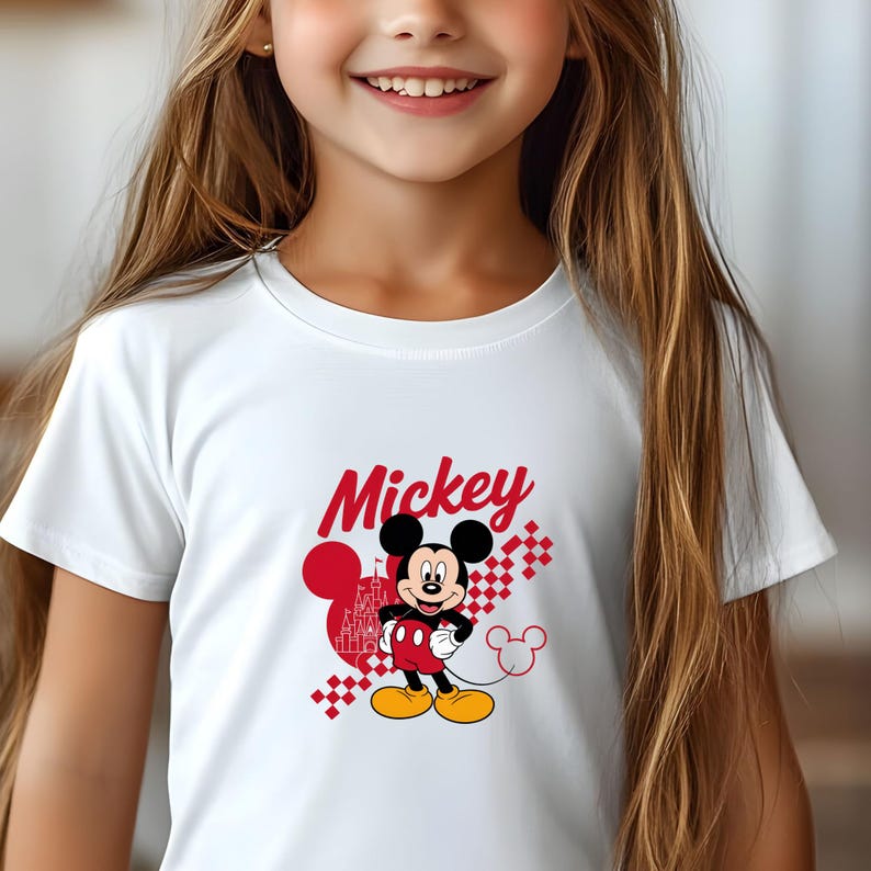 May include: White t-shirt featuring a graphic of Mickey Mouse. The design includes Mickey in red, black, and yellow, with the word "Mickey" in red script. A red heart and castle graphic are also present.